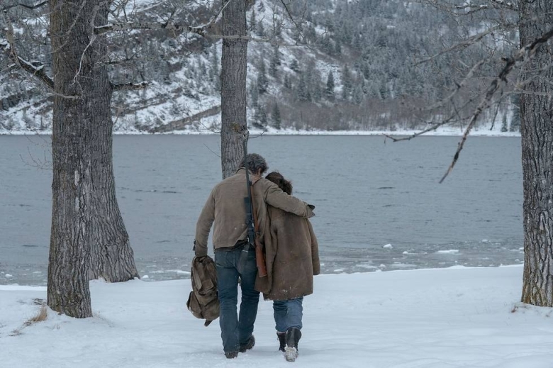 Pedro Pascal as Joel and Bella Ramsey as Ellie walking away in the snow in Episode 8 of The Last of Us