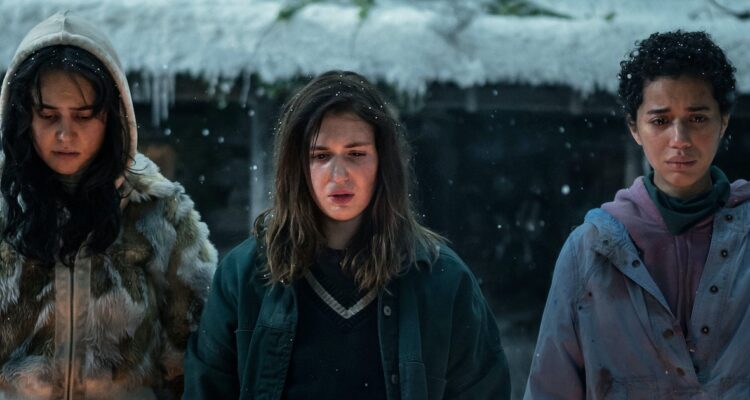 Teen Lottie, Shauna, and Taissa in Season 2 of Yellowjackets all standing in the snow in front of the cabin.