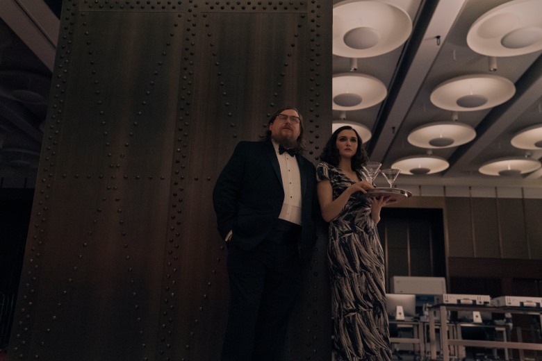 Rachel Weisz as Elliott Mantle and Michael Chernus as Tom in formal attire with a try of martinis looking over their new lab in Dead Ringers 