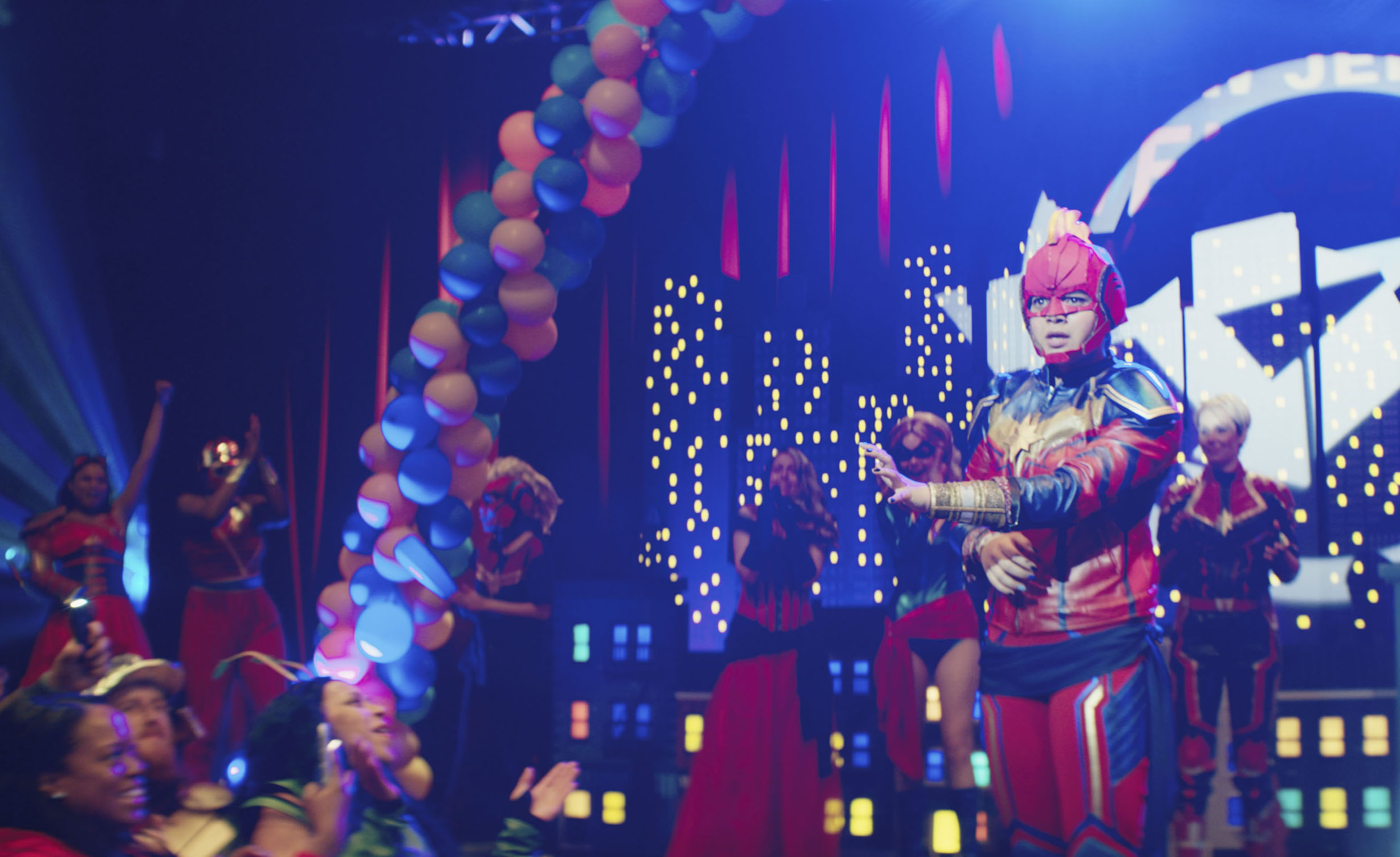 A teen girl in a homemade Captain Marvel costume takes the stage at a convention cosplay contest; still from Ms. Marvel